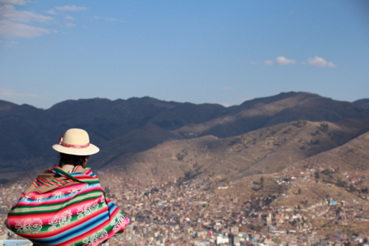 Rondreis Peru, Chili en Bolivia - Een Peruaanse dame kijkt vanuit de bergen uit over de stad Cusco